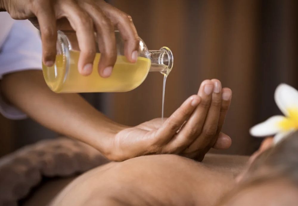 Warm aromatherapy oil being poured for a hot aroma oil massage in Athlone
