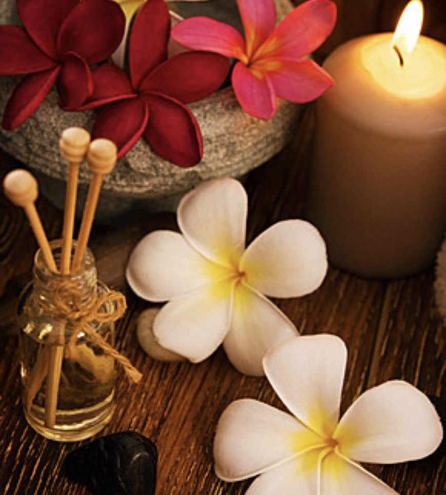 Frangipani flowers, aroma diffuser and candlelight in a Thai massage room